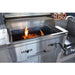 Stainless steel barbecue grill with flames inside, on a patio.